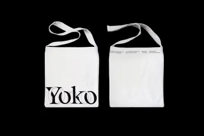 Two views of a white canvas tote bag featuring black typography and interlocking circles on a solid black background.