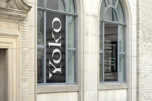 Yoko Ono brand identity display with typography on large arched windows of a stone building exterior