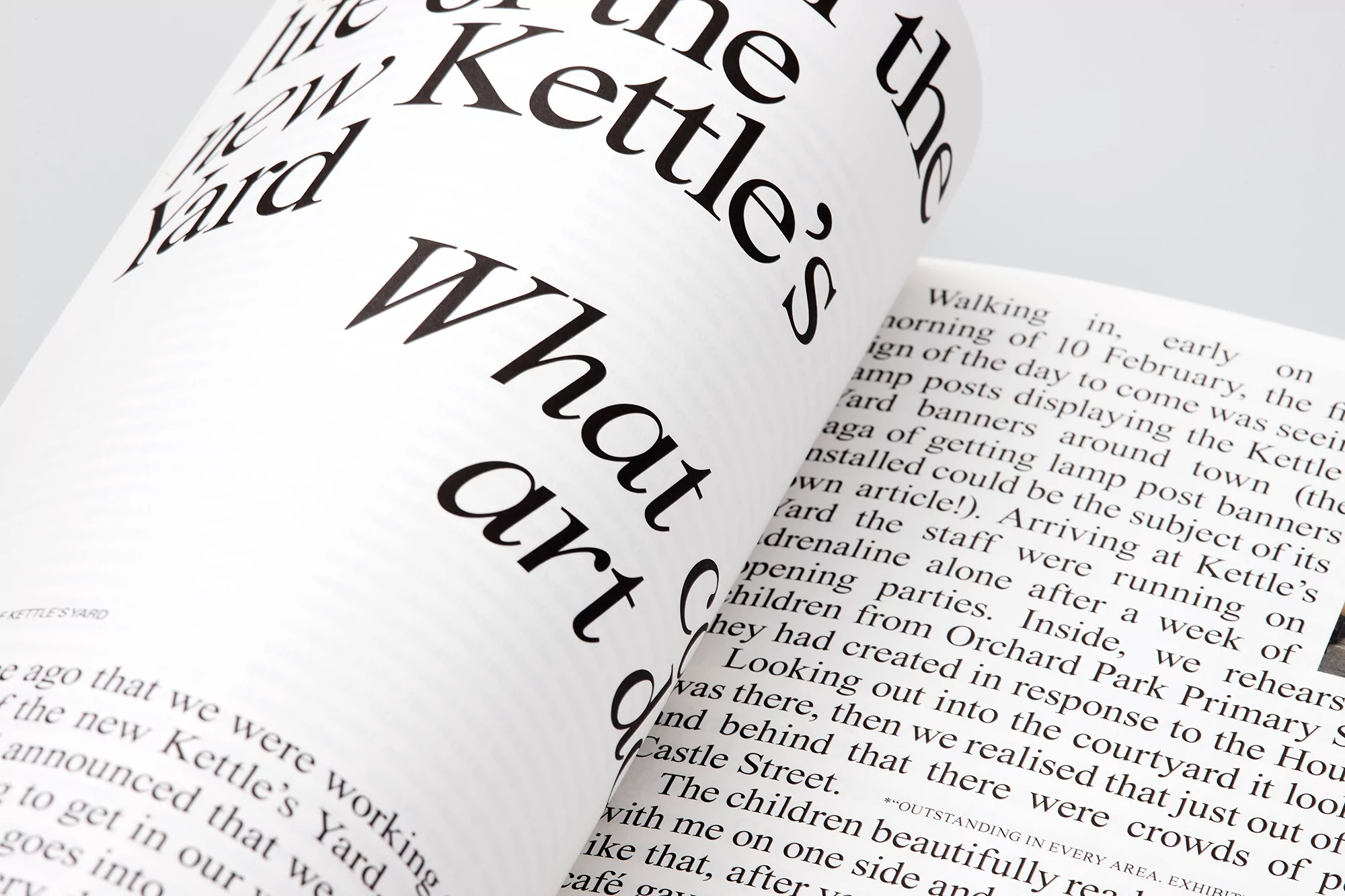 Open magazine spread with bold black typography on white pages, featuring article excerpts and design elements, creating a modern aesthetic.