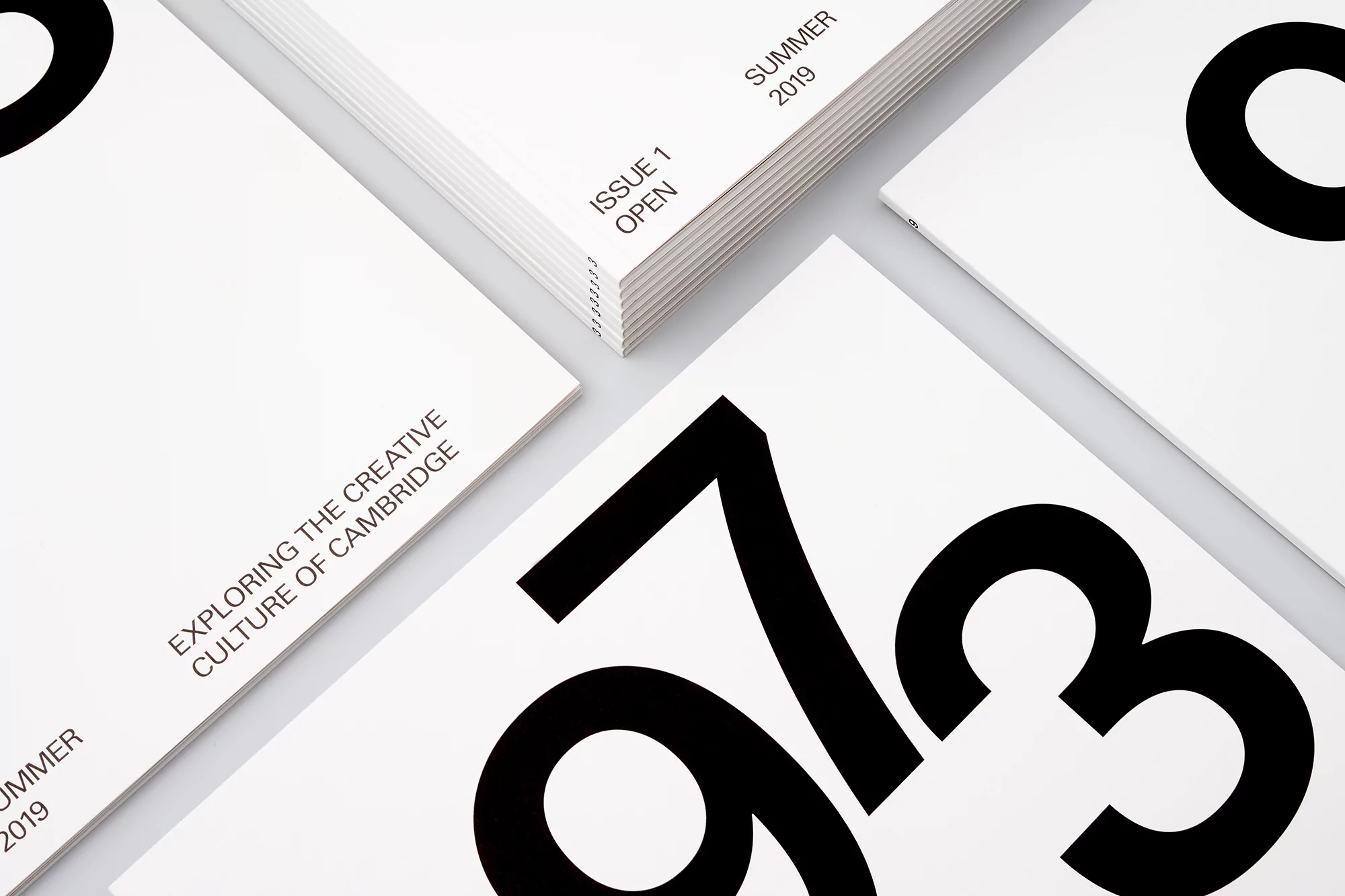 Several copies of a minimalist magazine cover, featuring bold black numbers and simple typography on a bright white background.