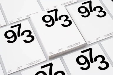 Stacked and scattered minimalist white magazine issues featuring bold black typography showing the number 973.