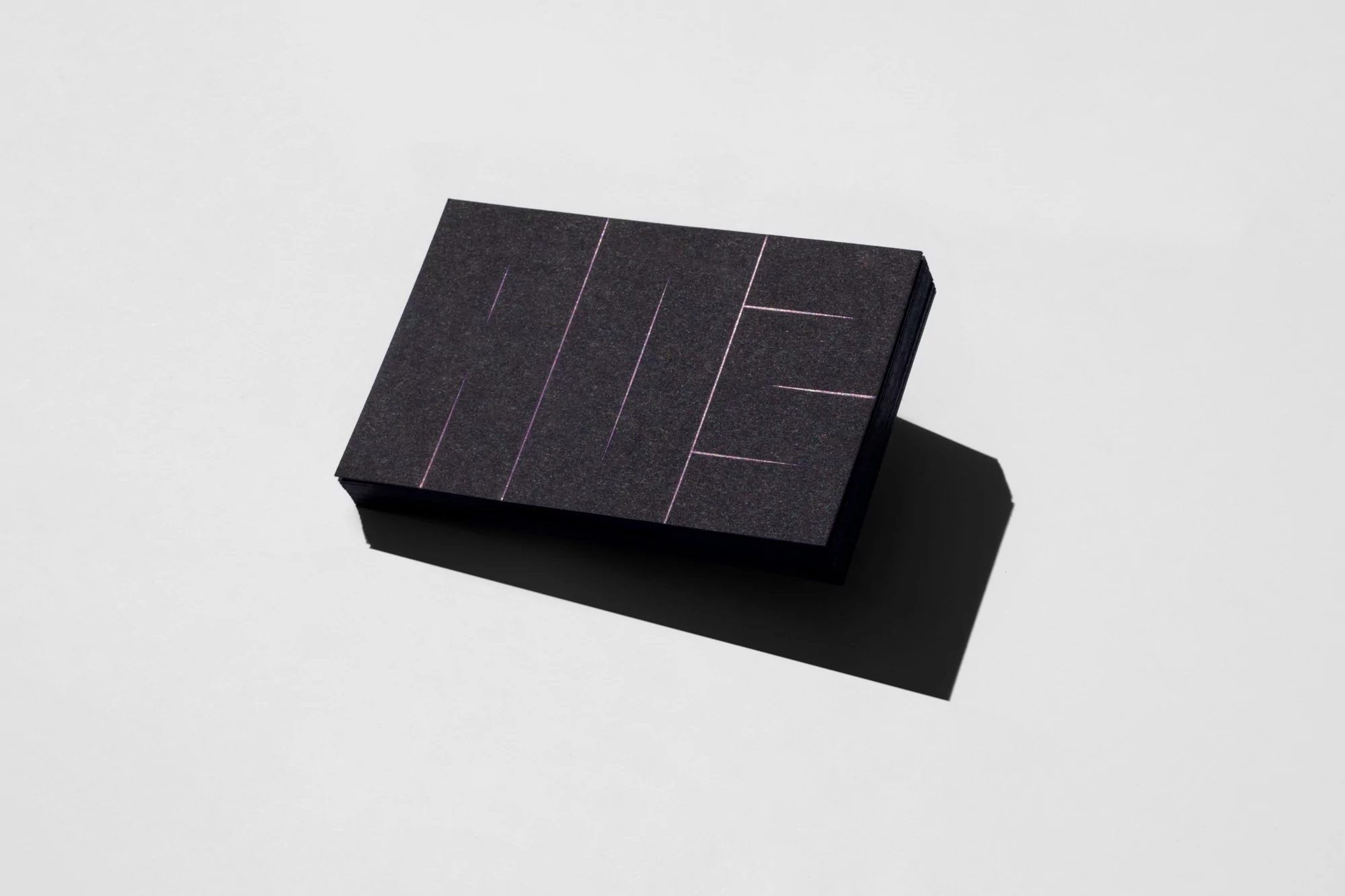 Angled studio shot of a dark gray rectangular box with linear geometric design on a white surface with shadow.