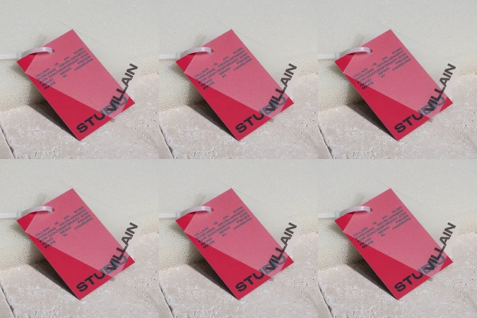 Multiple red tags with white lettering and a geometric color block, attached with plastic ties and set against a textured backdrop.
