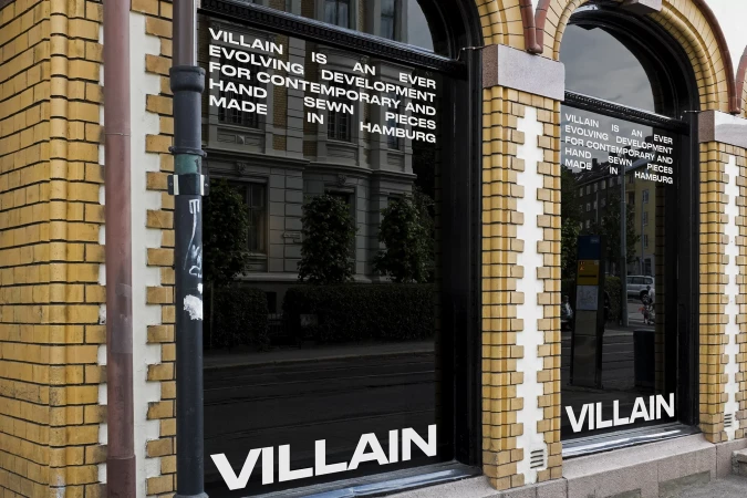 VILLAIN storefront with yellow brick facade, arched display windows, and bold white typographic window decals.