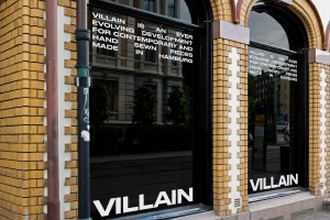 VILLAIN storefront with yellow brick facade, arched display windows, and bold white typographic window decals.