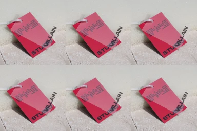 Pink paper tag with bold black typography and white plastic tie resting on a textured stone surface