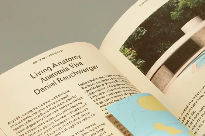 Book open to a page with architectural text and a photo of a modern building with a pool, featuring titles 'Living Anatomy' and 'Anatomia Viva'.