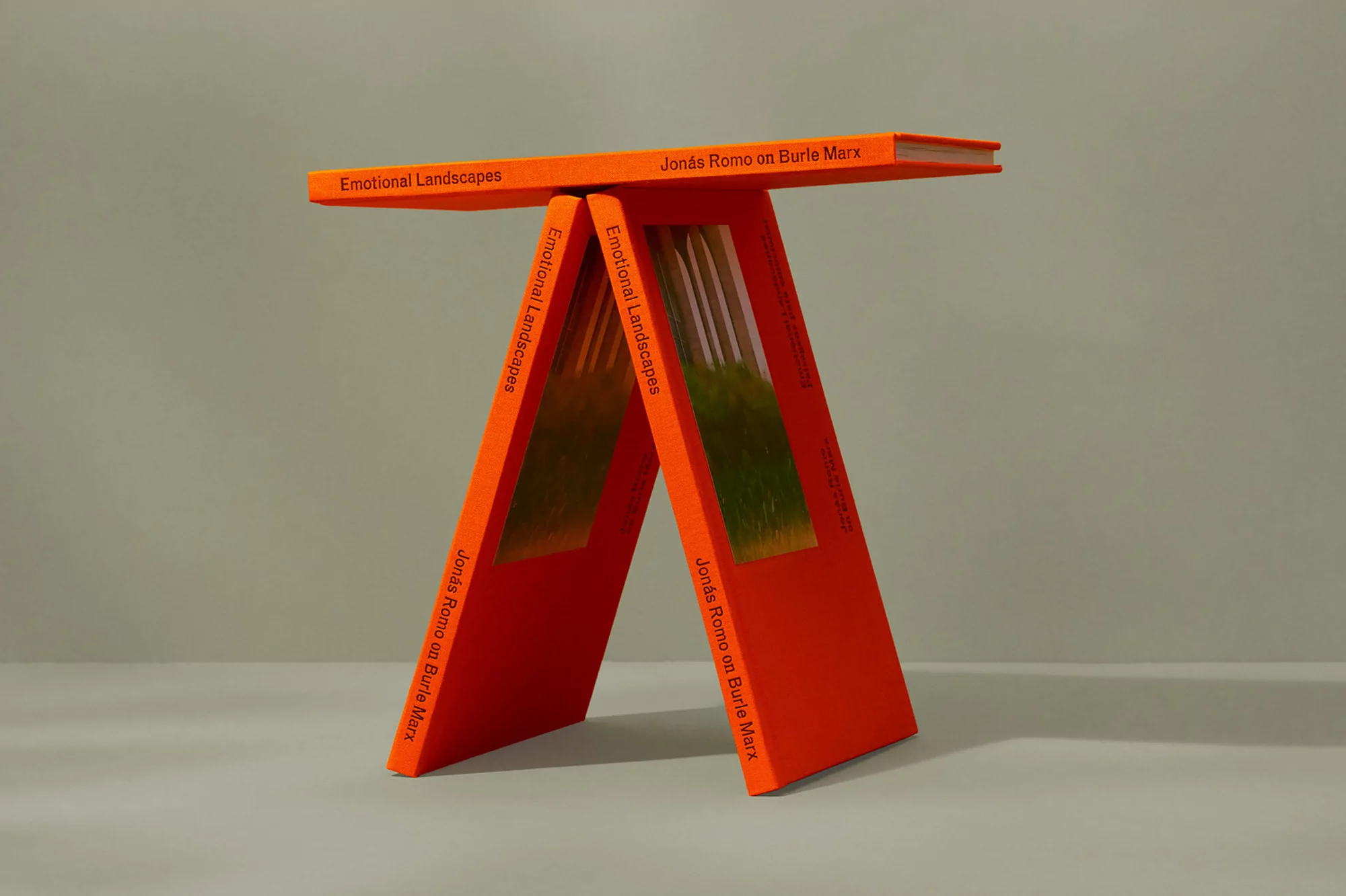Three orange books arranged to form a small table, showcasing cover text and green/brown colors from interior pages.