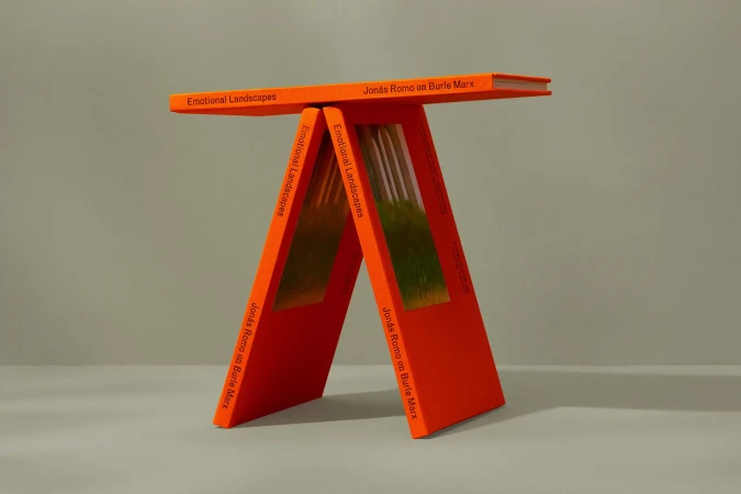 Three orange books arranged to form a small table, showcasing cover text and green/brown colors from interior pages.