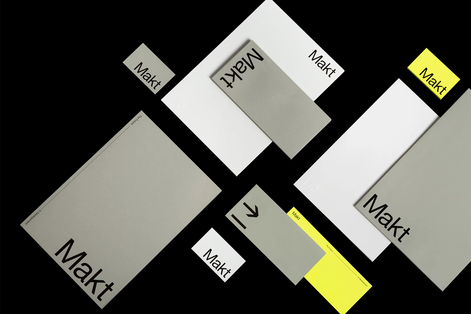 Arrangement of gray, white, and yellow paper rectangles with the word 'Makt' printed in black, set against a stark black background.