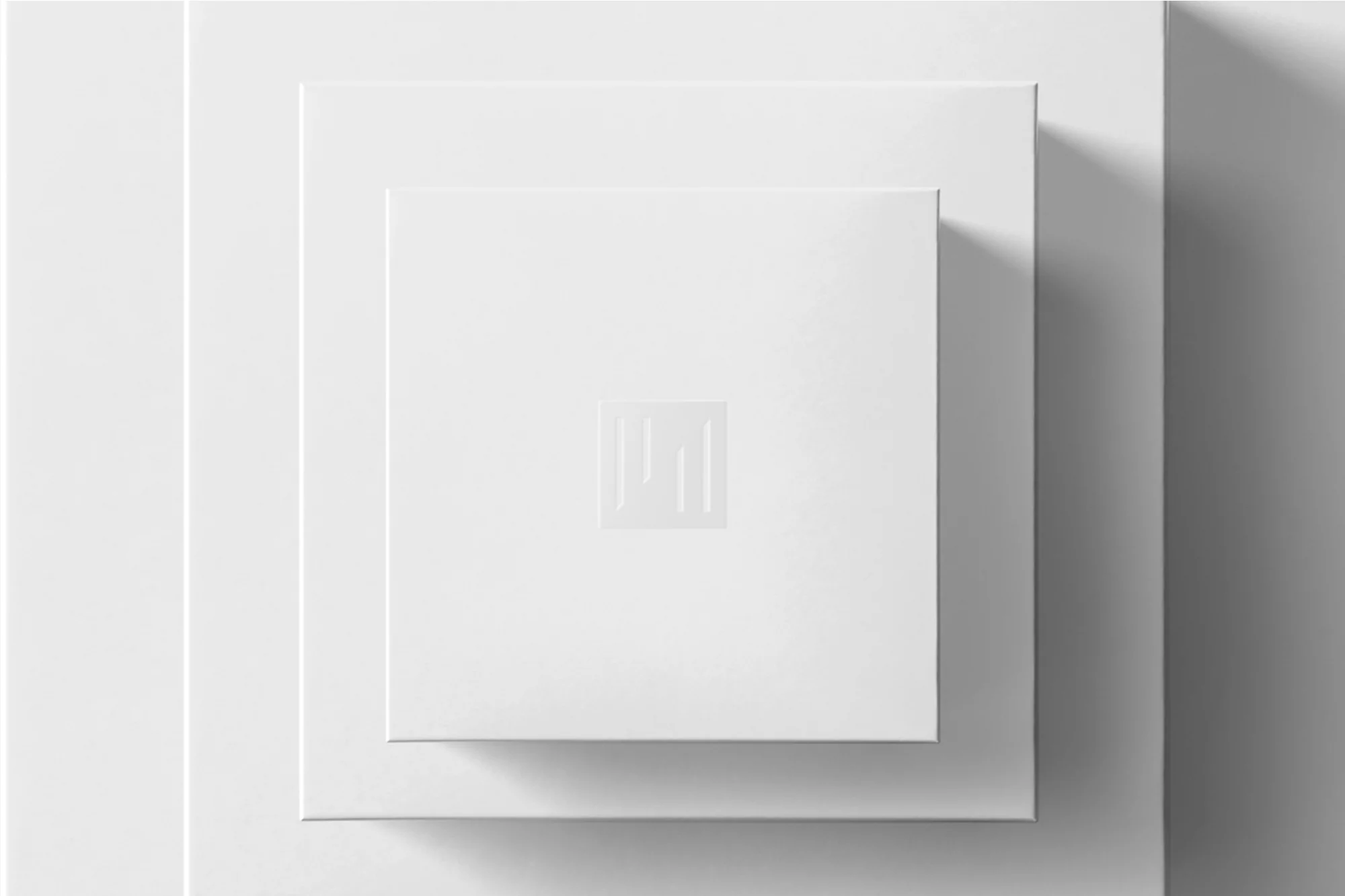 Overhead shot of nested square white boxes, minimalist design with geometric logo, casting soft shadows in a modern setting.