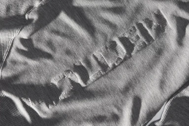 Monochrome knit fabric surface with the word Holden perforated or debossed into the textured material