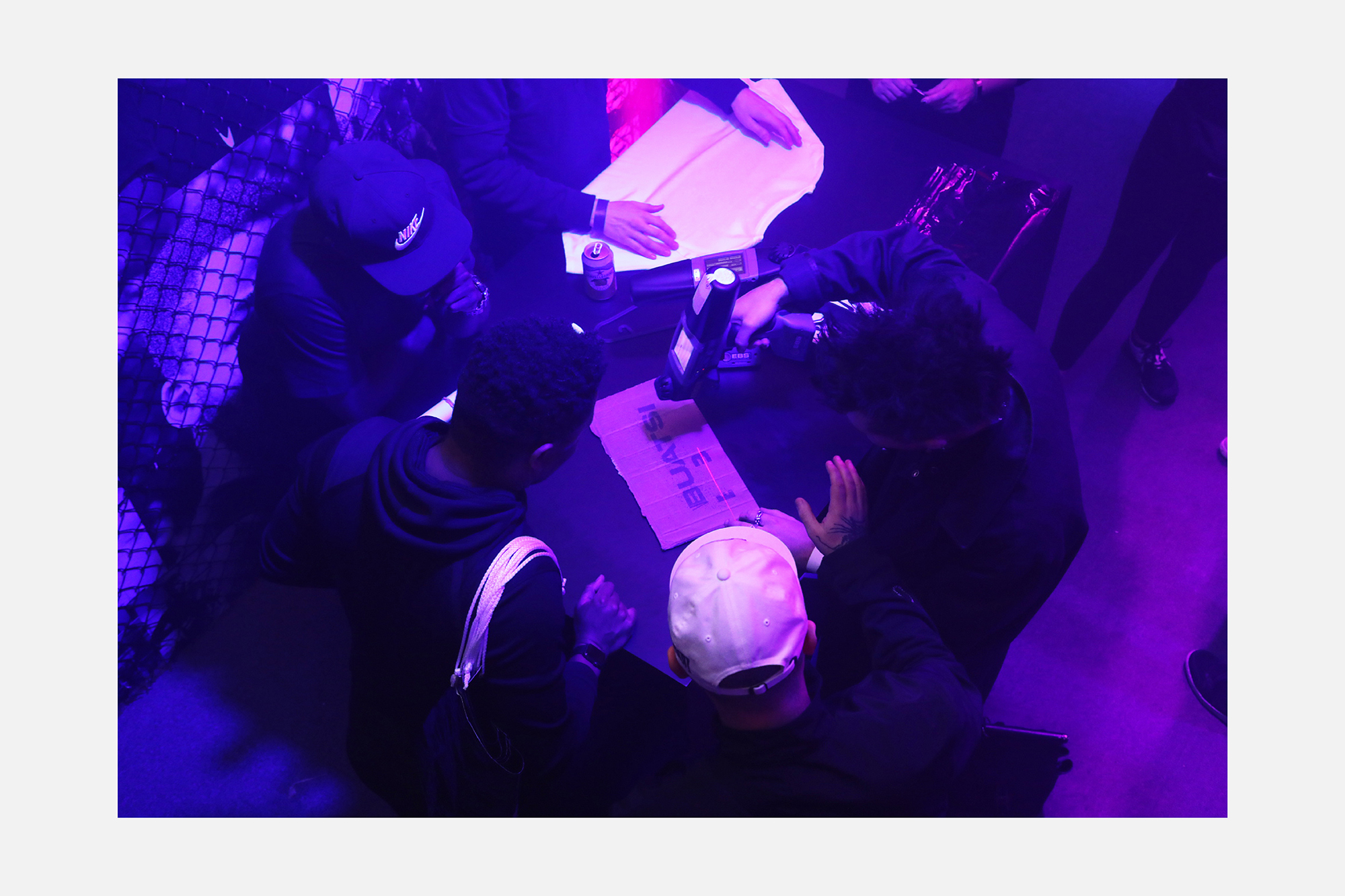 High angle shot of people gathered around a dark table under intense purple lighting working on brand design