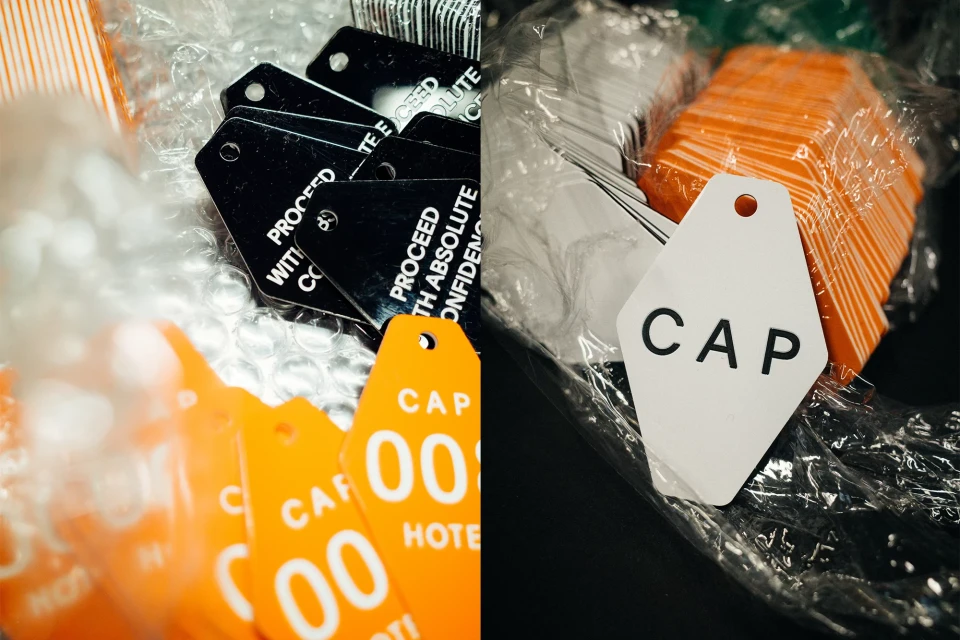 Close-up of a collection of orange, white, and black plastic key tags with text, stacked and packaged, under bright lighting, in a studio.