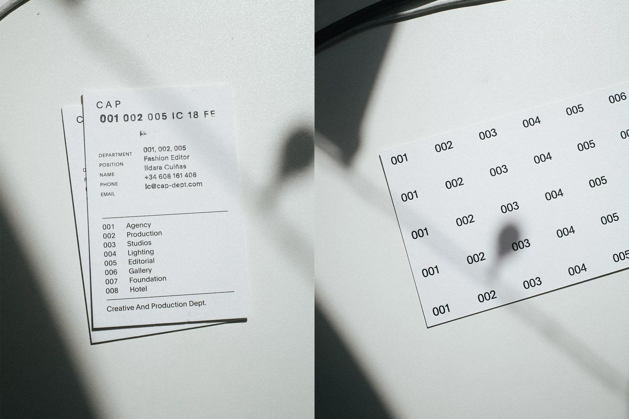 Close-up of two business cards on a white surface with shadow and text related to fashion, agency, studios, production, lighting, gallery.