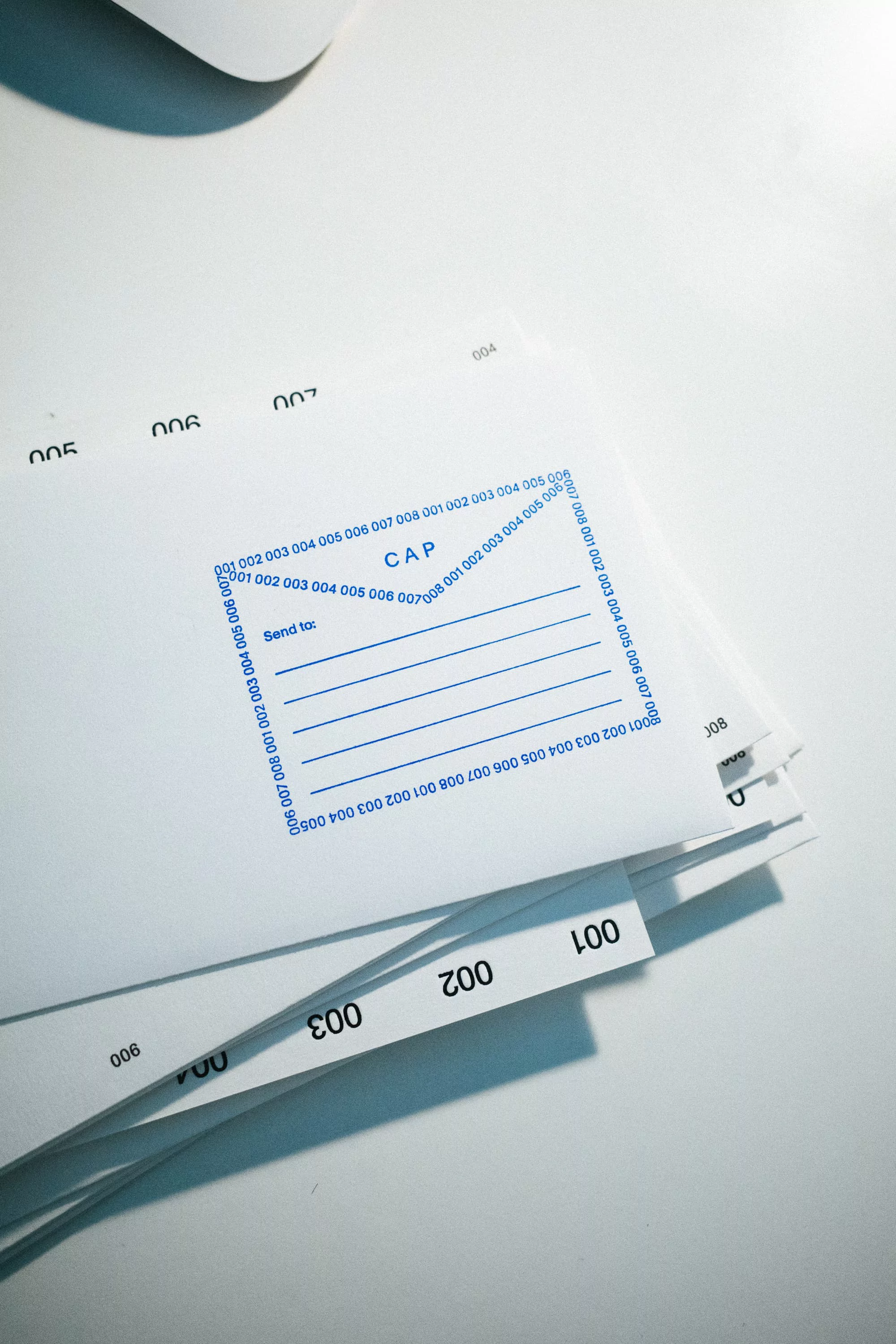 Stack of white sheets with numbered tabs and blue printed text on a white surface. Minimalist design highlights a clean, organized aesthetic.