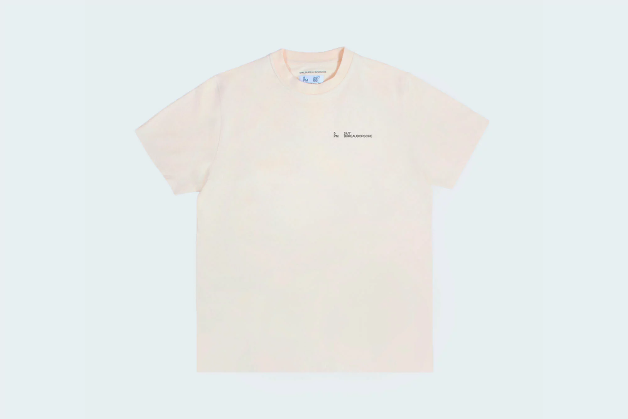 Cream-colored t-shirt with short sleeves, a round neck, and a small black logo on a pale-blue background, centered.