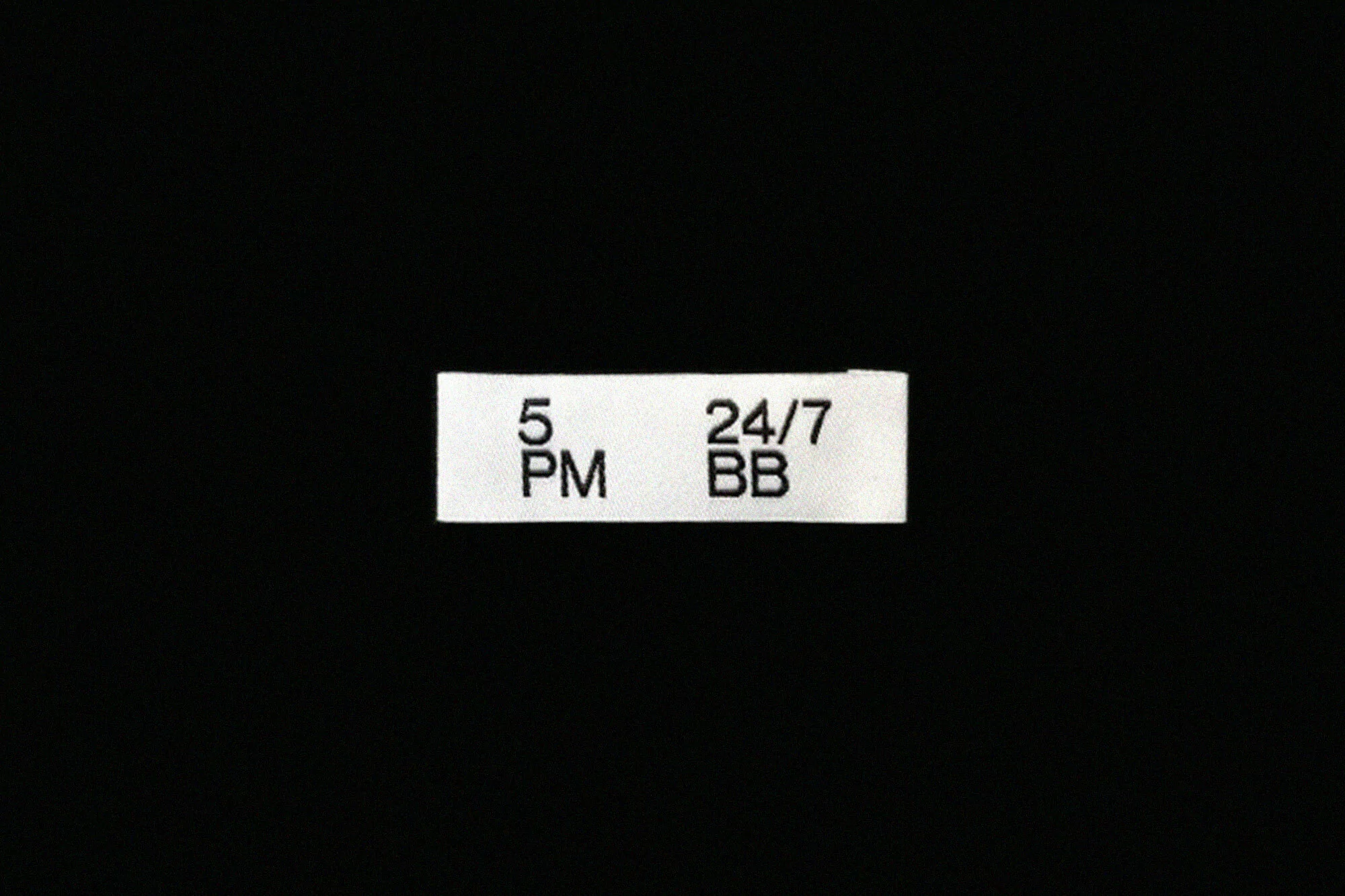 Text label on a black background displaying '5 PM' and '24/7 BB', indicating a time or service availability.