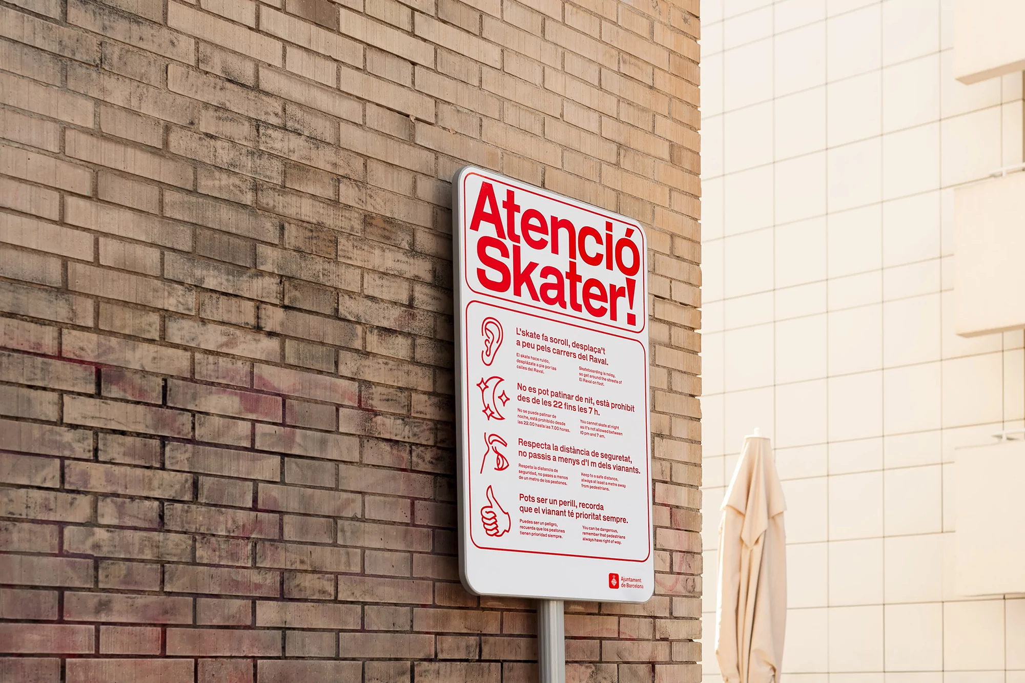 Skateboard safety sign in Catalan language on brick wall with rules and images for skaters, promoting responsible skateboarding.