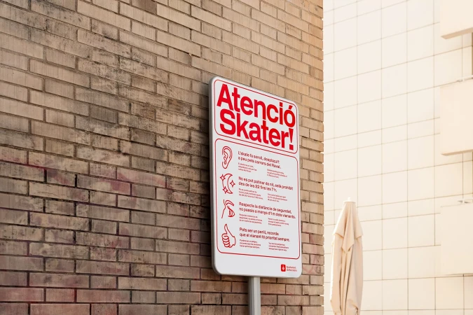 Skateboard safety sign in Catalan language on brick wall with rules and images for skaters, promoting responsible skateboarding.