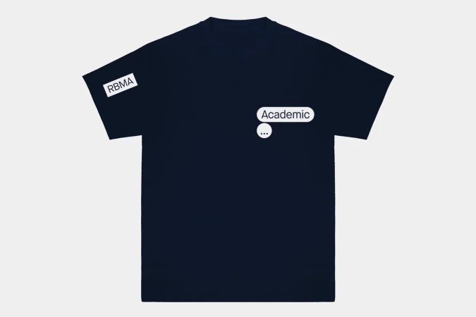 Dark blue t-shirt on a white surface with the text “Academic” and a message bubble printed on the front and RBMA on the sleeve.