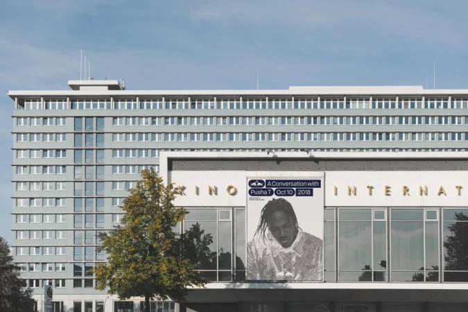 Building with large banner advertising 'A Conversation with Pusha T' event, featuring artist portrait and event details.