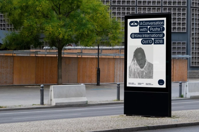 Outdoor advertising display featuring an advertisement for A Conversation with Pusha T at Kino International on Oct 10, 2018, in neutral tones.