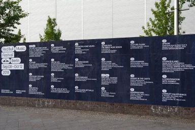 Large outdoor festival poster for Red Bull Music Festival Berlin 2018 mounted on a dark brick wall.