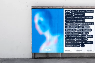 Red Bull Music Festival poster mounted on a concrete wall featuring a blurred blue portrait graphic and line-up text list