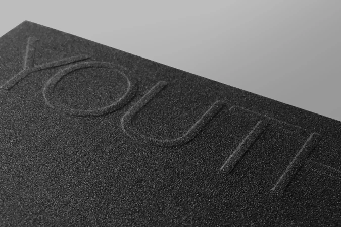 Close-up of a textured black surface with embossed letters spelling 'YOUR,' showcasing a minimalist and modern aesthetic.