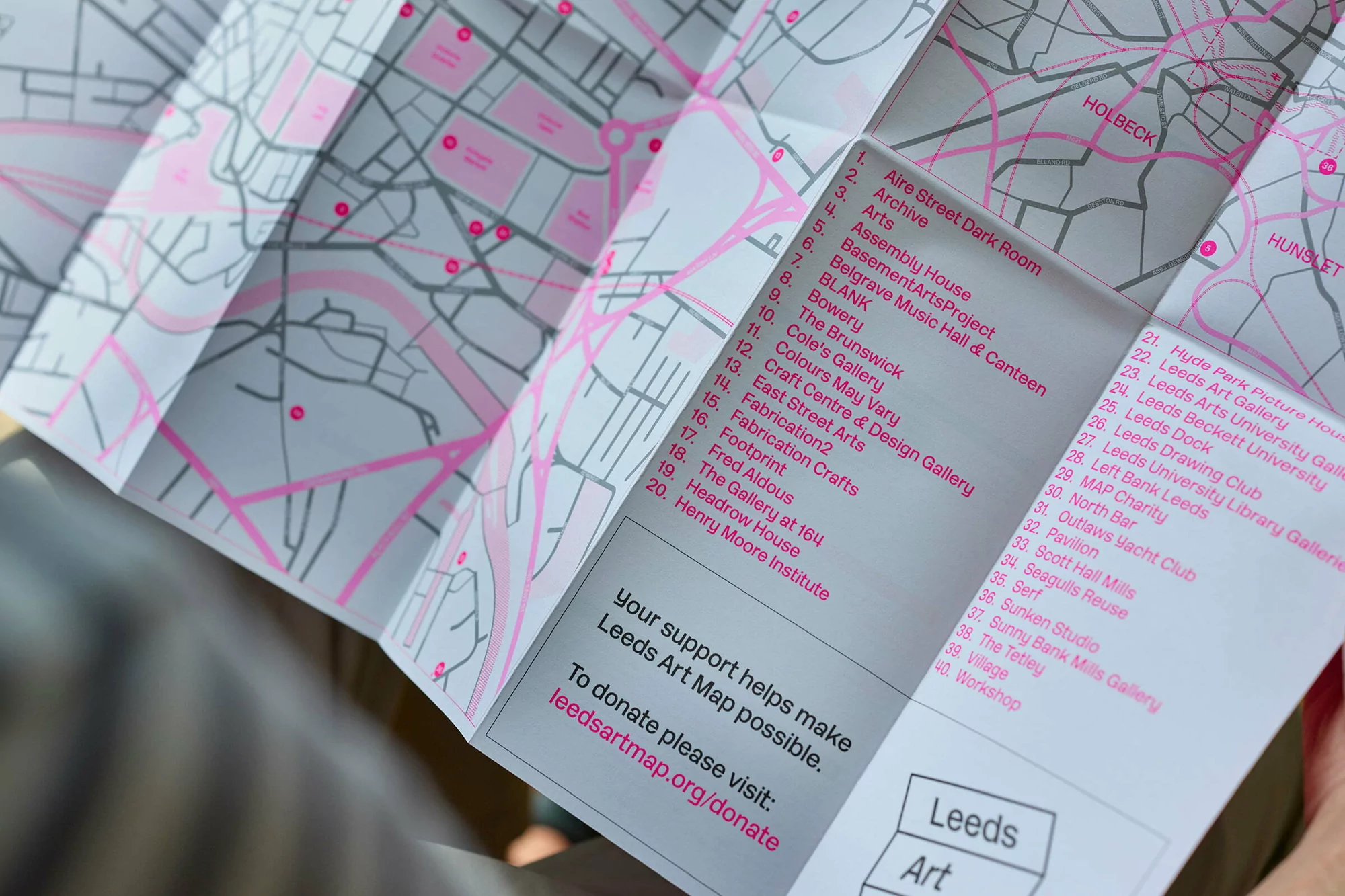 Close-up of a folded paper city map with pink accent lines and a numbered index list held in hands