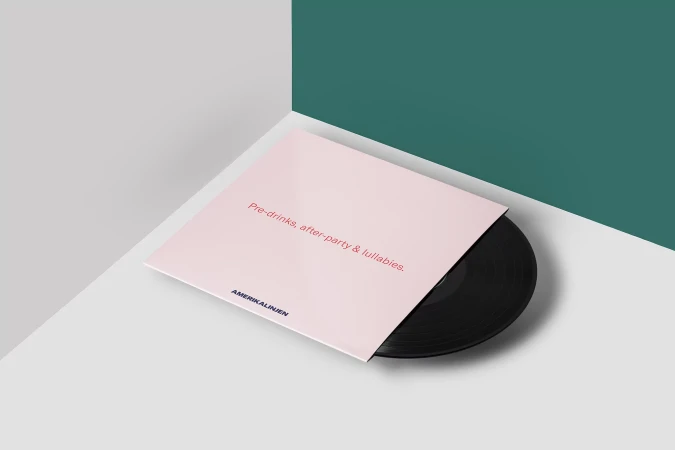 Vinyl record in a pink album cover featuring the text 'Pre-drinks, after-party & lullabies.' Minimalist studio shot with grey and teal background.