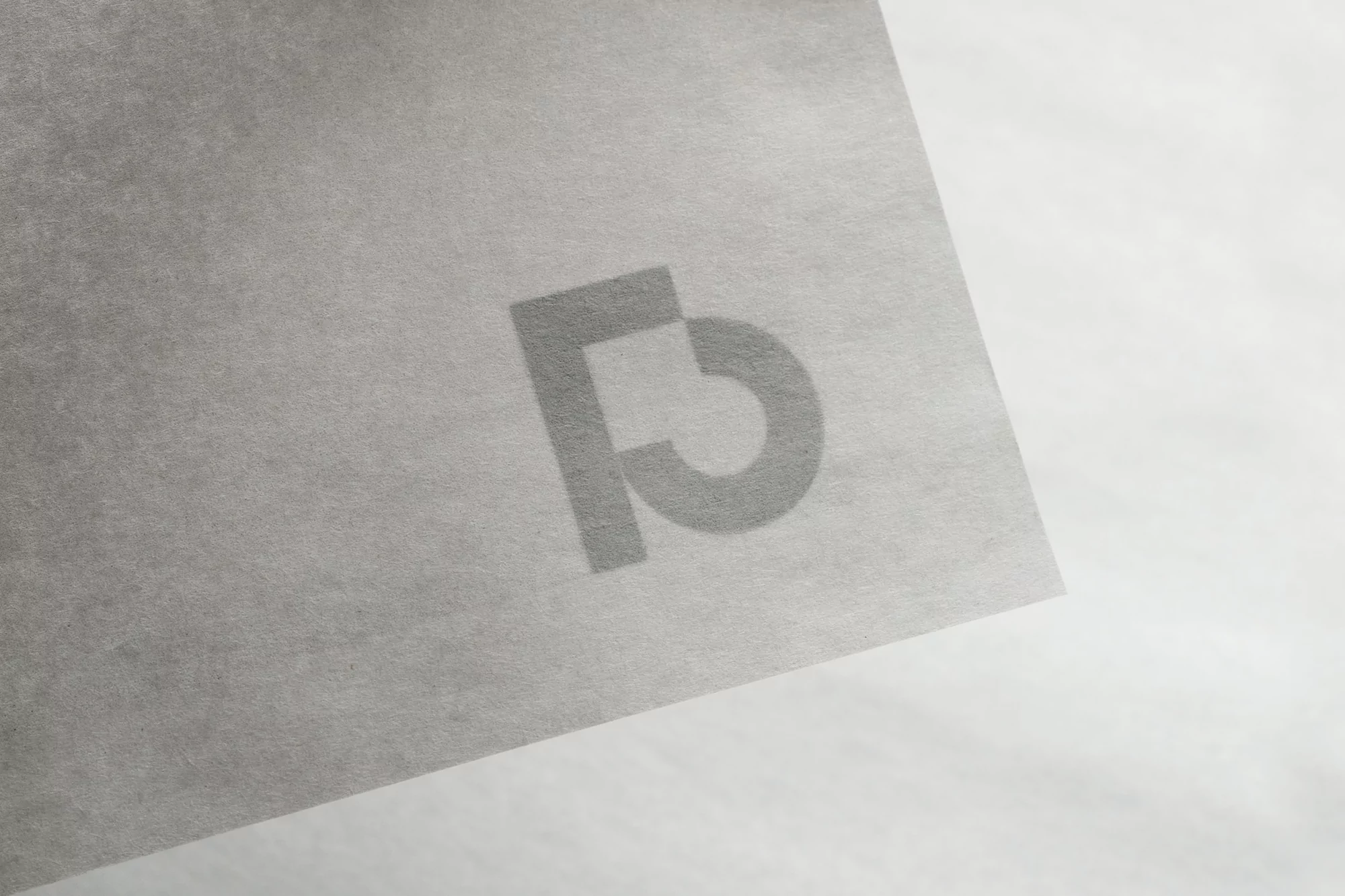 Minimalist image featuring a textured, grey paper with a faint, stylized logo in the center, creating a subtle, monochromatic aesthetic.