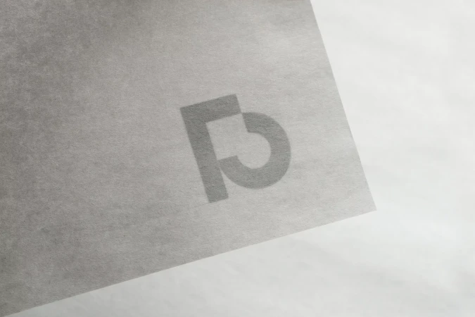 Minimalist image featuring a textured, grey paper with a faint, stylized logo in the center, creating a subtle, monochromatic aesthetic.