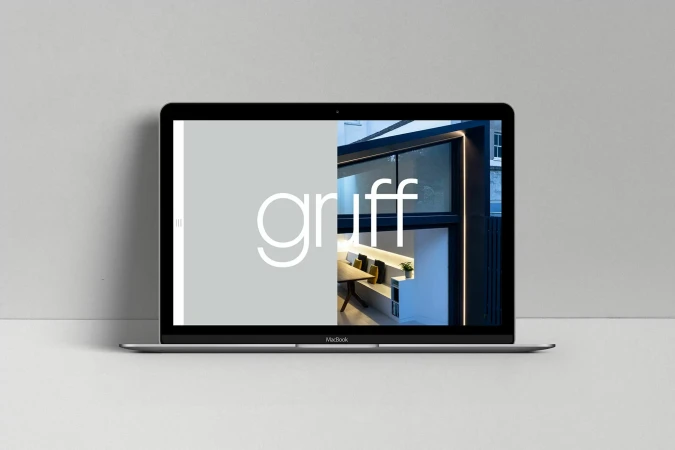 Laptop featuring the 'gruff' website, displaying an interior design showcase on its screen, set against a plain studio backdrop.