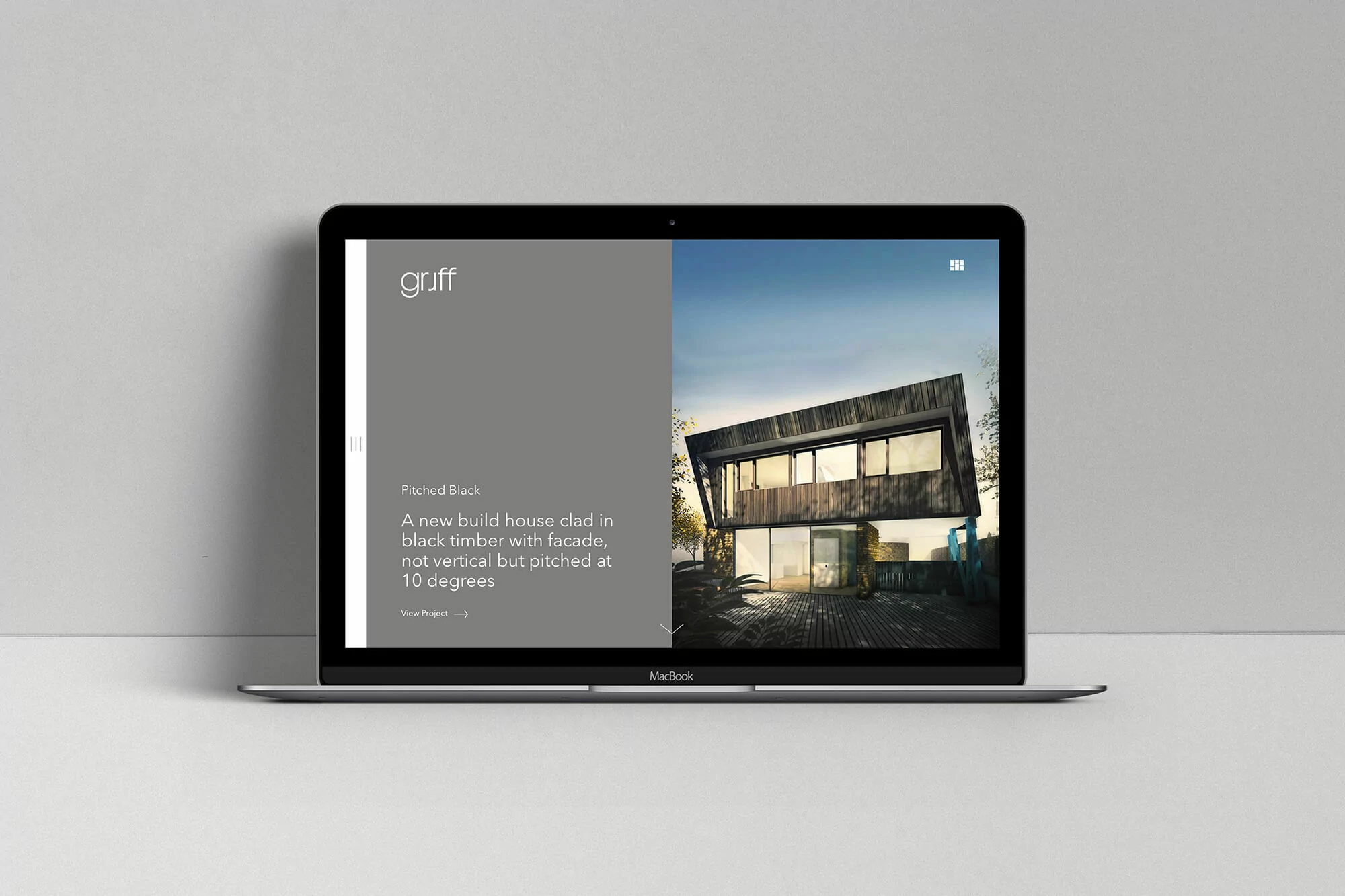 Laptop displaying modern house architecture design, featuring a black timber facade and pitched roof, showcased on a minimalist grey background.