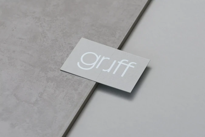 Business card with the white text "gruff" rests on a light gray textured surface next to a plain light gray surface.
