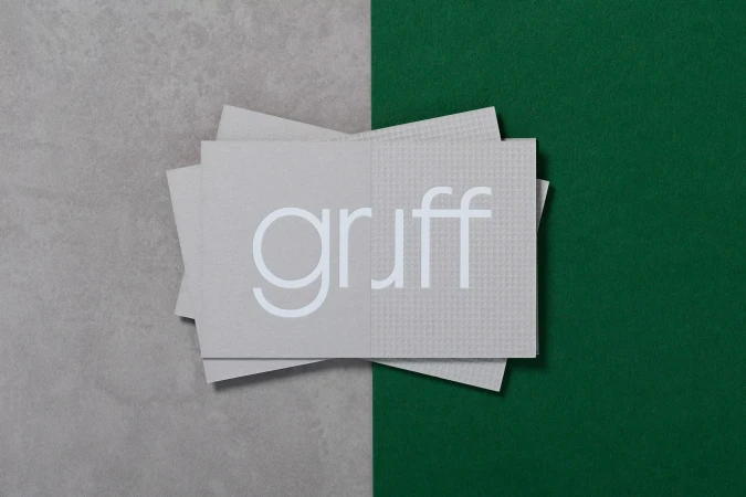 Stacked grey textured paper cards featuring the brand name Gruff on a divided grey and green background