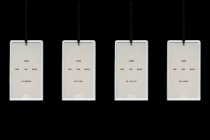 Four rectangular brand identity hang tags with black hanging cords displayed in a row against a solid black background.