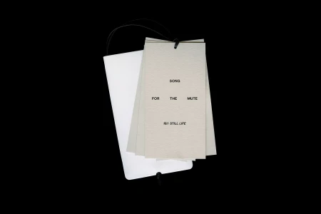 Stacked paper hang tags with black typography for Song for the Mute on a black background