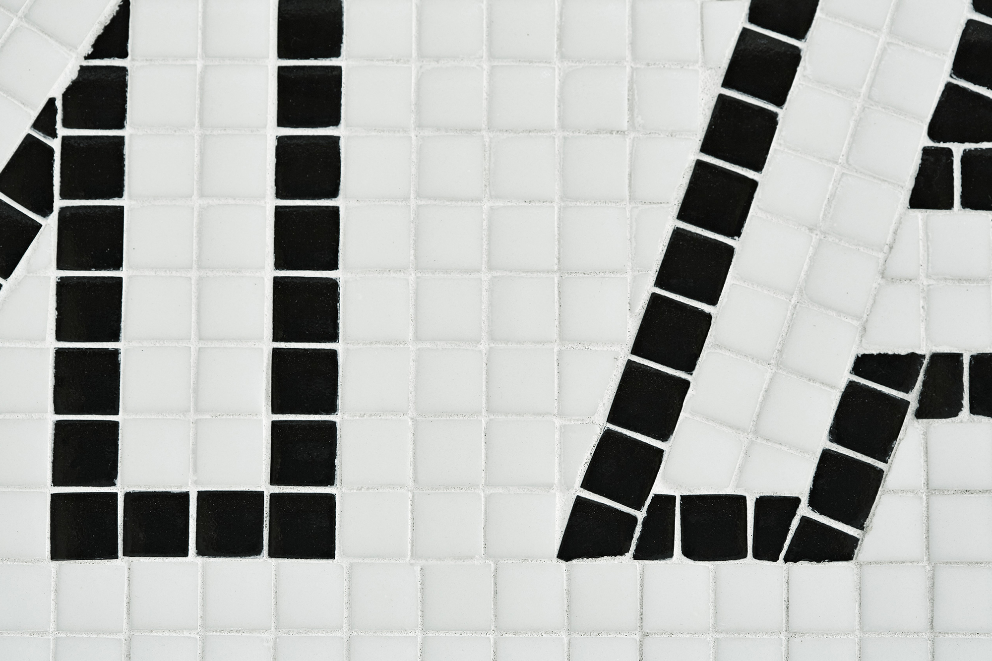 Abstract mosaic tile pattern featuring black shapes against a white background creating a geometric and textured surface design.
