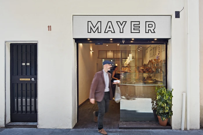 Exterior storefront of Mayer bakery with a person walking past in motion blur