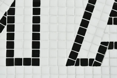 Close-up of black and white mosaic tile typography forming graphic letters on a flat surface
