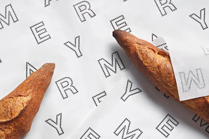 Fresh artisan baguettes resting on branded white paper with dotted typography for Mayer brand identity.