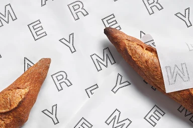 Fresh artisan baguettes resting on branded white paper with dotted typography for Mayer brand identity.