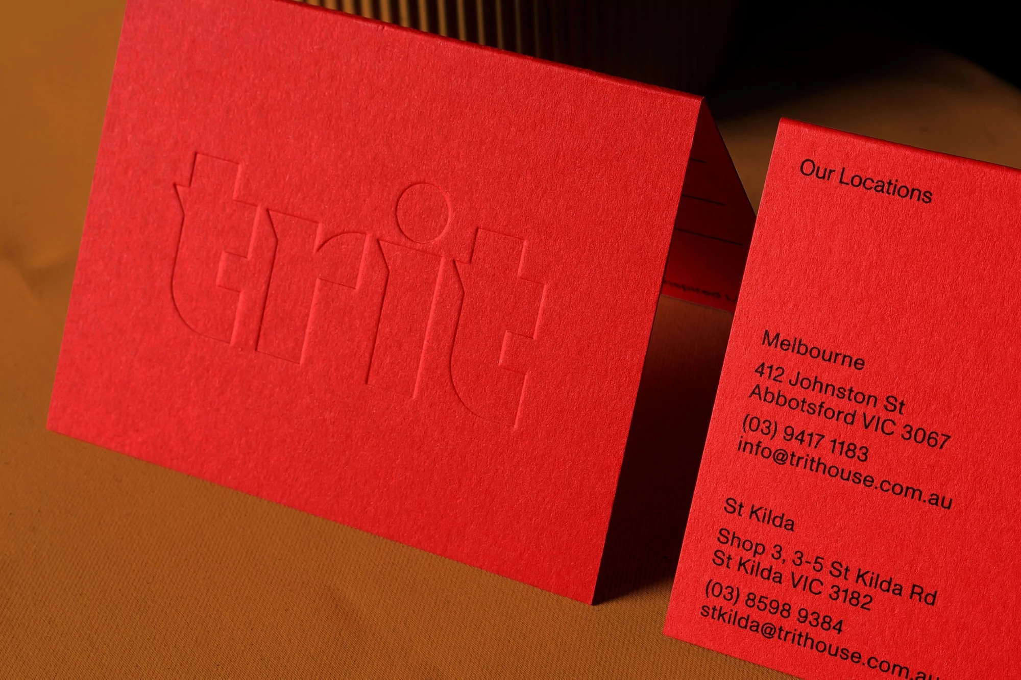 Close-up of two red business cards with embossed and printed text featuring company information and logos.