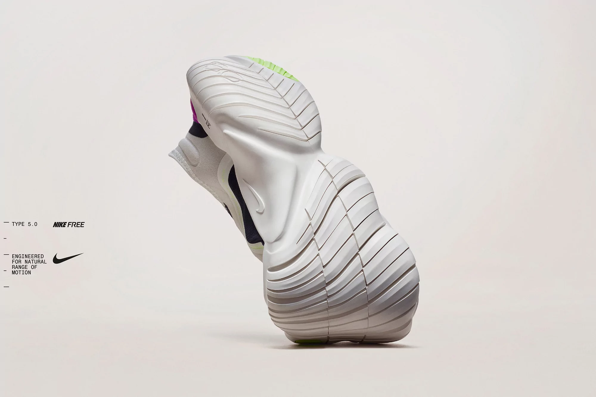 Studio shot showcasing the sole of a white Nike Free running shoe with a grey studio background. The sole has a segmented, flexible design.