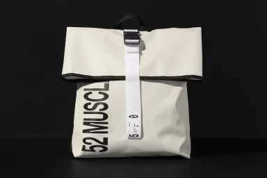 White rolltop backpack with bold black text and a white vertical strap on a black surface.