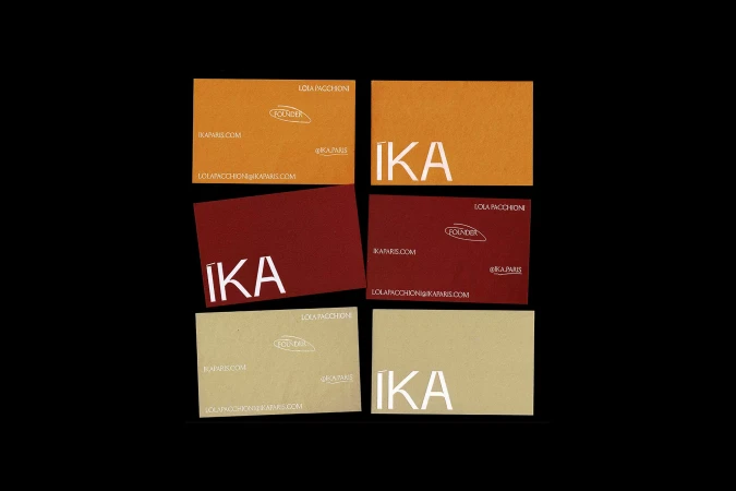 Multiple business cards in shades of brown and red are displayed against a black backdrop, showcasing the brand 'IKA' in bold white lettering.