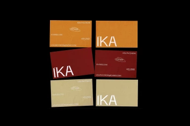 Collection of business cards in orange, red, and beige displaying the IKA brand identity against a black background.